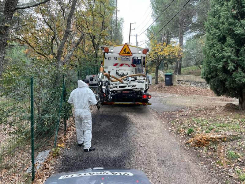 Opérateur tenant le bras du blowpatcher pour la projection d'enrobé en vue de la réparation d'un nid de poule sur route communale à Aubagne